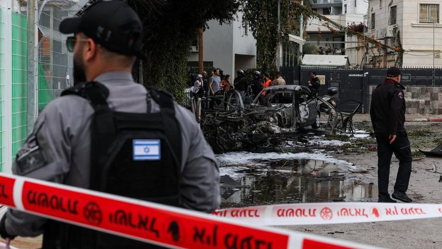 People gather near destroyed vehicles following an Iranian projectile strike, amid the U.S.-Israeli conflict with Iran, in central Israel, March 15, 2026. REUTERS/Tyrone Siu