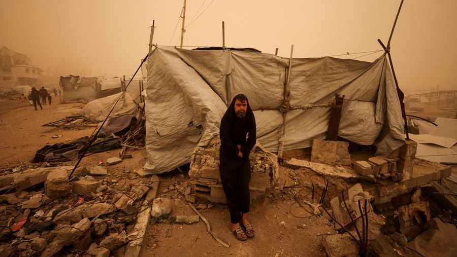 Palestinians walk amid a sandstorm in a tent camp sheltering Palestinians displaced during the two-year Israeli offensive, in Khan Younis in the southern Gaza Strip, March 14, 2026. REUTERS/Ramadan Abed