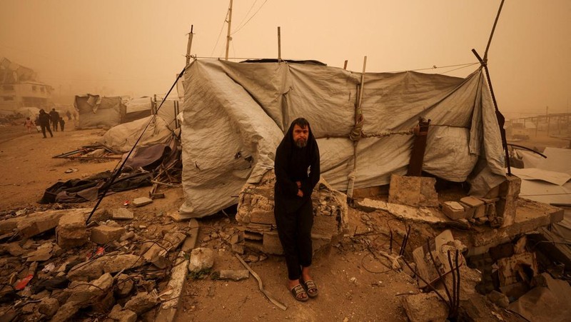 Palestinians walk amid a sandstorm in a tent camp sheltering Palestinians displaced during the two-year Israeli offensive, in Khan Younis in the southern Gaza Strip, March 14, 2026. REUTERS/Ramadan Abed
