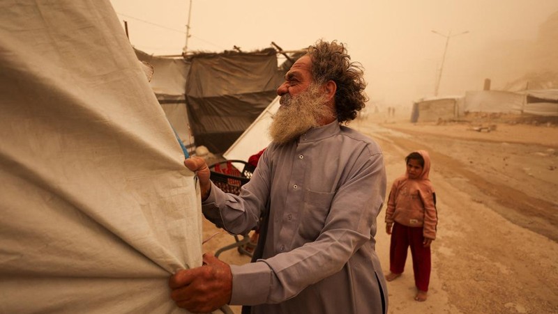 Palestinians walk amid a sandstorm in a tent camp sheltering Palestinians displaced during the two-year Israeli offensive, in Khan Younis in the southern Gaza Strip, March 14, 2026. REUTERS/Ramadan Abed