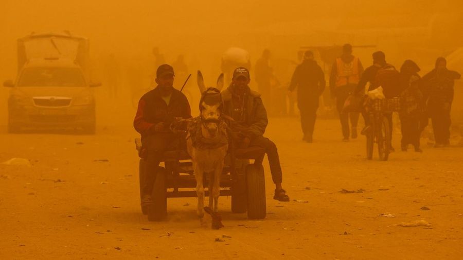 Palestinians walk amid a sandstorm in a tent camp sheltering Palestinians displaced during the two-year Israeli offensive, in Khan Younis in the southern Gaza Strip, March 14, 2026. REUTERS/Ramadan Abed