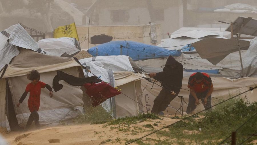 Palestinians walk amid a sandstorm in a tent camp sheltering Palestinians displaced during the two-year Israeli offensive, in Khan Younis in the southern Gaza Strip, March 14, 2026. REUTERS/Ramadan Abed