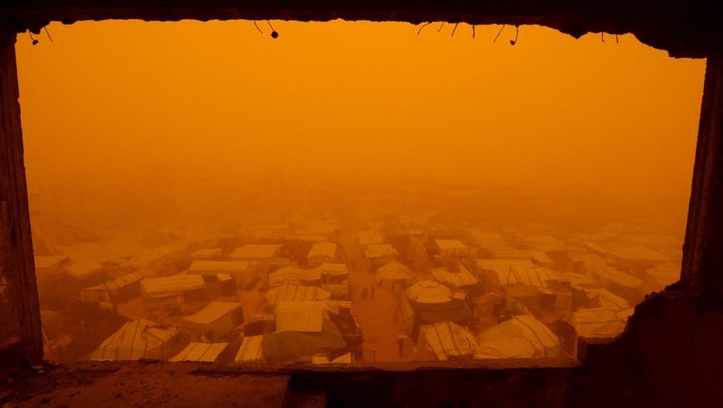 Palestinians walk amid a sandstorm in a tent camp sheltering Palestinians displaced during the two-year Israeli offensive, in Khan Younis in the southern Gaza Strip, March 14, 2026. REUTERS/Ramadan Abed