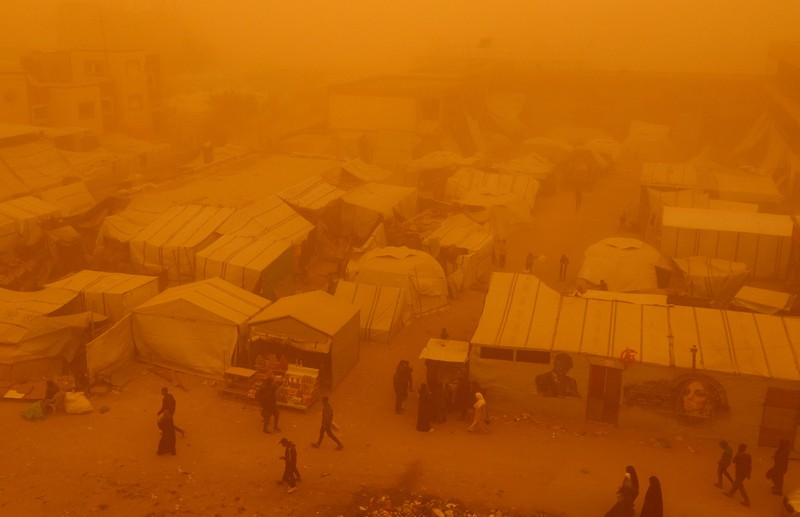 Palestinians walk amid a sandstorm in a tent camp sheltering Palestinians displaced during the two-year Israeli offensive, in Khan Younis in the southern Gaza Strip, March 14, 2026. REUTERS/Ramadan Abed