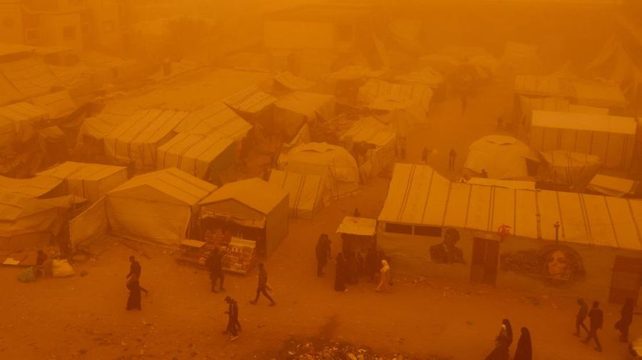 Palestinians walk amid a sandstorm in a tent camp sheltering Palestinians displaced during the two-year Israeli offensive, in Khan Younis in the southern Gaza Strip, March 14, 2026. REUTERS/Ramadan Abed