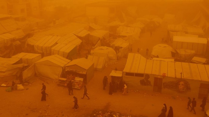 Palestinians walk amid a sandstorm in a tent camp sheltering Palestinians displaced during the two-year Israeli offensive, in Khan Younis in the southern Gaza Strip, March 14, 2026. REUTERS/Ramadan Abed