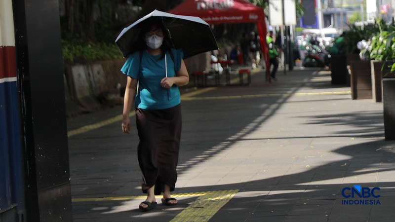 Warga berjalan dengan menutup kepala untuk berlindung dari terik matahari di kawasan Dukuh Atas, Jakarta, Selasa (17/3/2026). (CNBC Indonesia/Muhammad Sabki)
