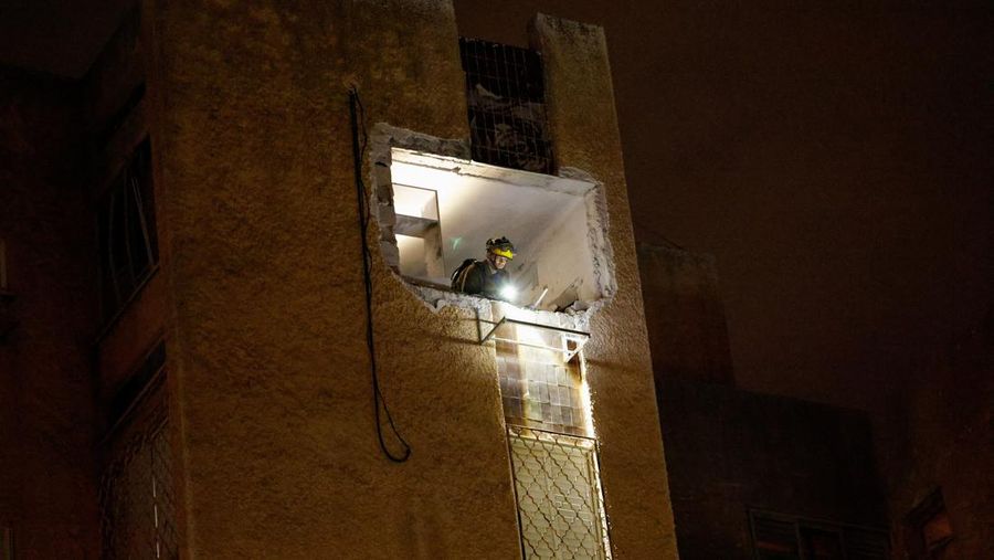 Bangunan yang rusak di lokasi dampak, setelah rentetan rudal yang diluncurkan dari Iran, di Tel Aviv, Israel, Kamis (19/3/2026) dini hari. (REUTERS/Amir Cohen)