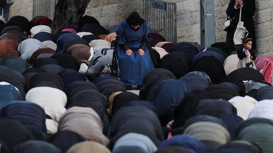 Para jamaah Muslim Palestina berdoa di tepi jalan untuk menandai berakhirnya bulan puasa suci Ramadan, karena mereka tidak diizinkan untuk menghadiri salat Idul Fitri di kompleks Al-Aqsa, yang juga dikenal oleh orang Yahudi sebagai Bukit Bait Suci, menyusul pembatasan berkumpul dalam kelompok besar, di tengah konflik AS-Israel dengan Iran, di Yerusalem, 20 Maret 2026. (REUTERS/Ammar Awad)
