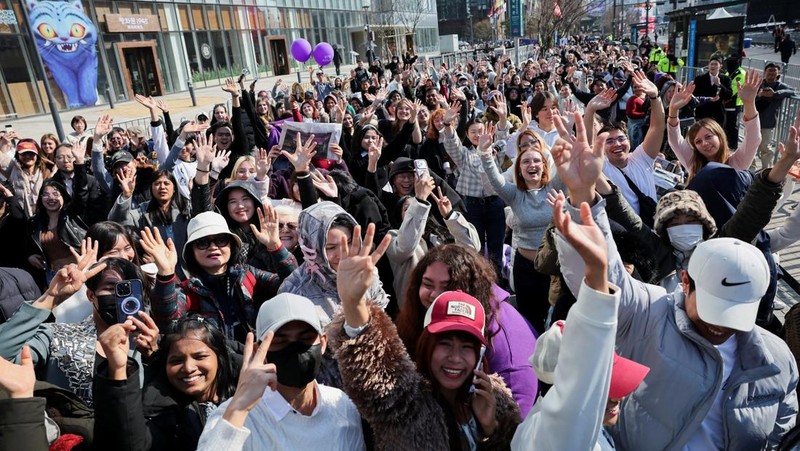 Para penggemar grup Kpop BTS bersorak menjelang konser 'BTS The Comeback Live Arirang' saat mereka menunggu di dekat lokasi konser, di pusat kota Seoul, Korea Selatan, 21 Maret 2026. (REUTERS/Kim Hong-ji)