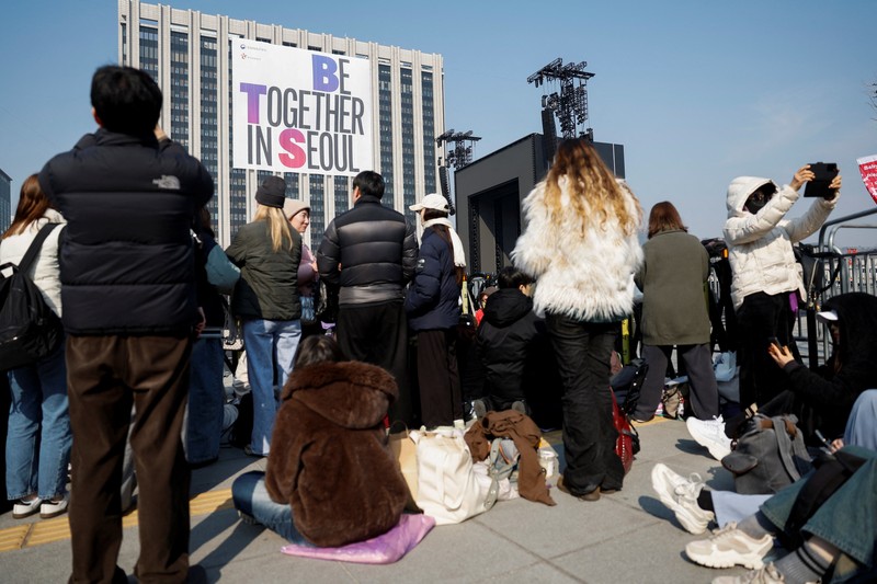 Para penggemar grup Kpop BTS bersorak menjelang konser 'BTS The Comeback Live Arirang' saat mereka menunggu di dekat lokasi konser, di pusat kota Seoul, Korea Selatan, 21 Maret 2026. (REUTERS/Kim Hong-ji)