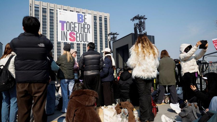 Para penggemar grup Kpop BTS bersorak menjelang konser 'BTS The Comeback Live Arirang' saat mereka menunggu di dekat lokasi konser, di pusat kota Seoul, Korea Selatan, 21 Maret 2026. (REUTERS/Kim Hong-ji)