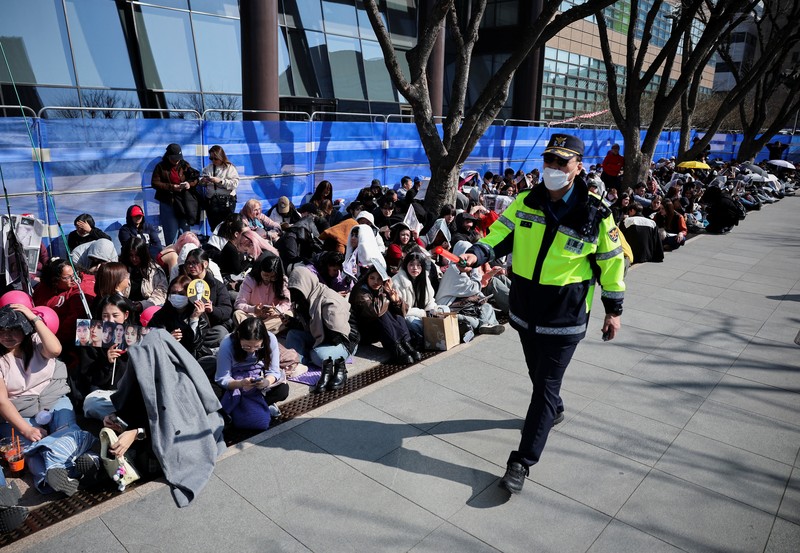 Para penggemar grup Kpop BTS bersorak menjelang konser 'BTS The Comeback Live Arirang' saat mereka menunggu di dekat lokasi konser, di pusat kota Seoul, Korea Selatan, 21 Maret 2026. (REUTERS/Kim Hong-ji)