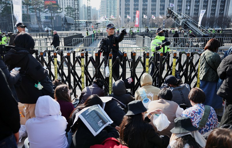 Para penggemar grup Kpop BTS bersorak menjelang konser 'BTS The Comeback Live Arirang' saat mereka menunggu di dekat lokasi konser, di pusat kota Seoul, Korea Selatan, 21 Maret 2026. (REUTERS/Kim Hong-ji)