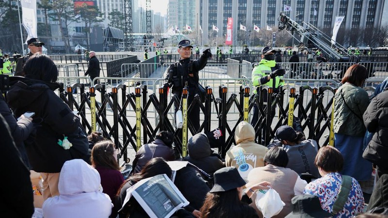 Para penggemar grup Kpop BTS bersorak menjelang konser 'BTS The Comeback Live Arirang' saat mereka menunggu di dekat lokasi konser, di pusat kota Seoul, Korea Selatan, 21 Maret 2026. (REUTERS/Kim Hong-ji)