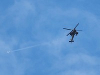 Sebuah pesawat terbang melintas di atas helikopter Apache Israel di dekat perbatasan Israel dengan Lebanon, di tengah eskalasi antara Hizbullah yang didukung Iran dan Israel serta konflik AS-Israel dengan Iran, di Israel utara, 22 Maret 2026. (REUTER
