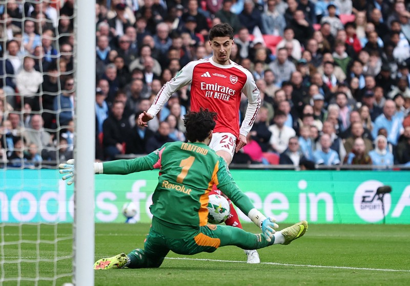 Para pemain Manchester City, termasuk Erling Haaland, Ruben Dias, dan Rodri, merayakan kemenangan dengan mengangkat trofi Piala Carabao di podium setelah final melawan Arsenal di Stadion Wembley, London, Inggris, 22 Maret 2026. (Action Images via Reuters/Paul Childs)