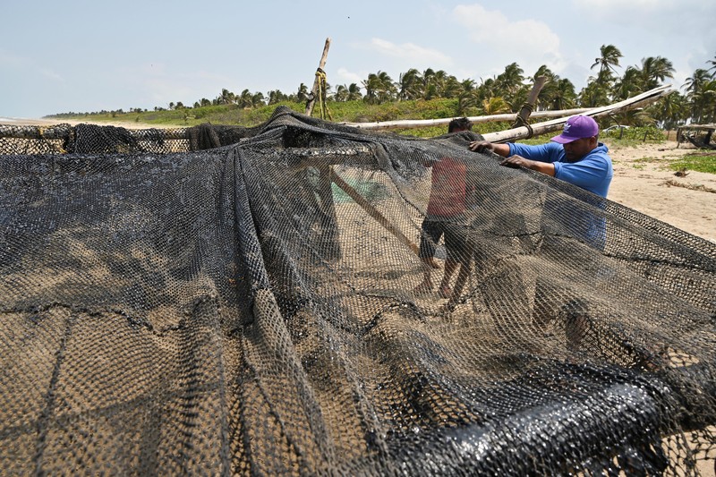 Para nelayan berdiri di dekat jaring ikan yang ternoda minyak akibat tumpahan minyak yang telah memengaruhi nelayan dan berbagai komunitas pesisir di Paylebot, negara bagian Tabasco, Meksiko, 22 Maret 2026. (REUTERS/Luis Manuel Lopez)