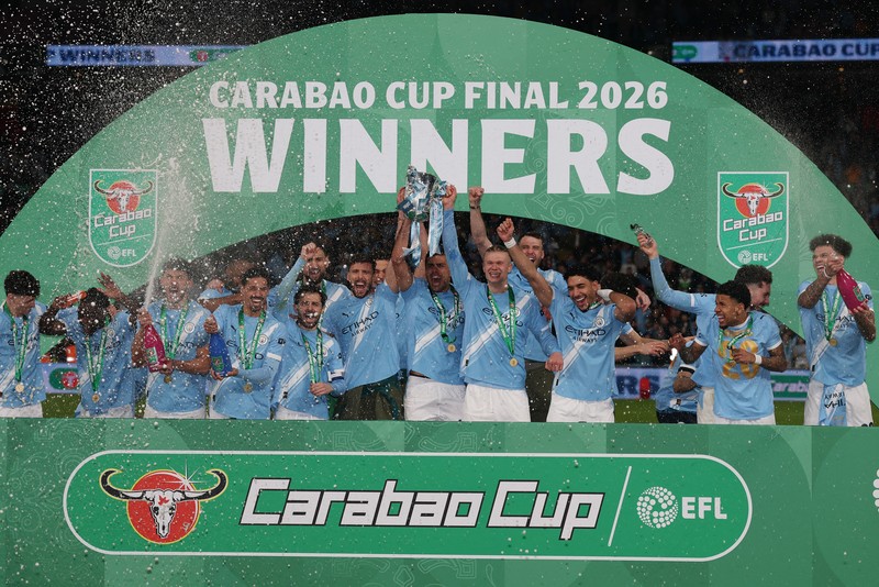Para pemain Manchester City, termasuk Erling Haaland, Ruben Dias, dan Rodri, merayakan kemenangan dengan mengangkat trofi Piala Carabao di podium setelah final melawan Arsenal di Stadion Wembley, London, Inggris, 22 Maret 2026. (Action Images via Reuters/Paul Childs)
