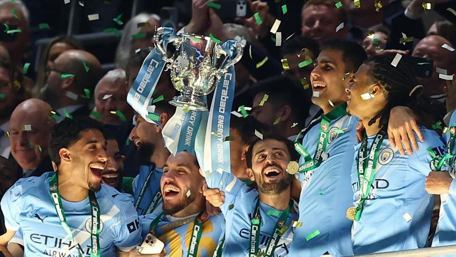 Para pemain Manchester City, termasuk Erling Haaland, Ruben Dias, dan Rodri, merayakan kemenangan dengan mengangkat trofi Piala Carabao di podium setelah final melawan Arsenal di Stadion Wembley, London, Inggris, 22 Maret 2026. (Action Images via Reuters/Paul Childs)