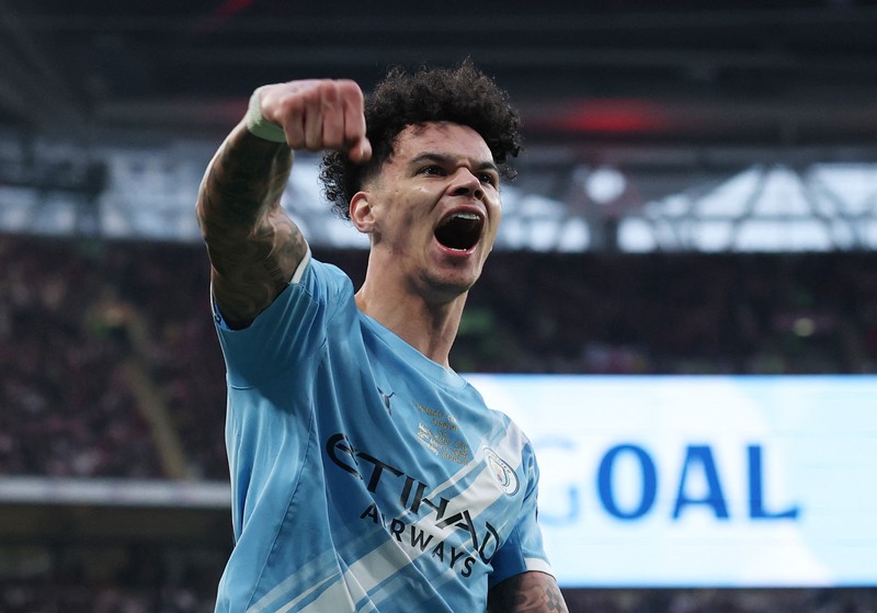 Para pemain Manchester City, termasuk Erling Haaland, Ruben Dias, dan Rodri, merayakan kemenangan dengan mengangkat trofi Piala Carabao di podium setelah final melawan Arsenal di Stadion Wembley, London, Inggris, 22 Maret 2026. (Action Images via Reuters/Paul Childs)