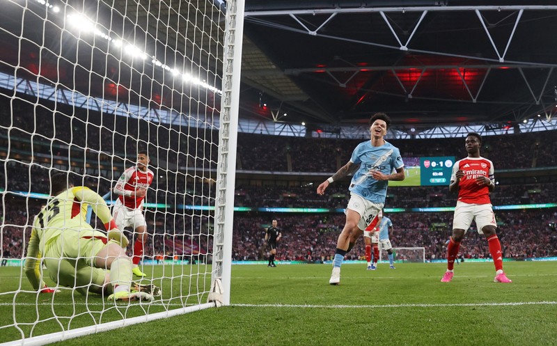 Para pemain Manchester City, termasuk Erling Haaland, Ruben Dias, dan Rodri, merayakan kemenangan dengan mengangkat trofi Piala Carabao di podium setelah final melawan Arsenal di Stadion Wembley, London, Inggris, 22 Maret 2026. (Action Images via Reuters/Paul Childs)