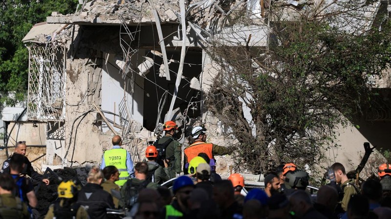 Anggota tim penyelamat bekerja di samping bangunan yang hancur di lokasi kejadian setelah serangan rudal Iran di Israel tengah, di tengah konflik AS-Israel dengan Iran, di Tel Aviv, Israel, Selasa (24/3/2026). (REUTERS/Tomer Appelbaum)