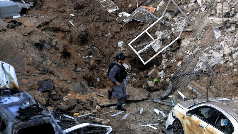 Anggota tim penyelamat bekerja di samping bangunan yang hancur di lokasi kejadian setelah serangan rudal Iran di Israel tengah, di tengah konflik AS-Israel dengan Iran, di Tel Aviv, Israel, Selasa (24/3/2026). (REUTERS/Tomer Appelbaum)