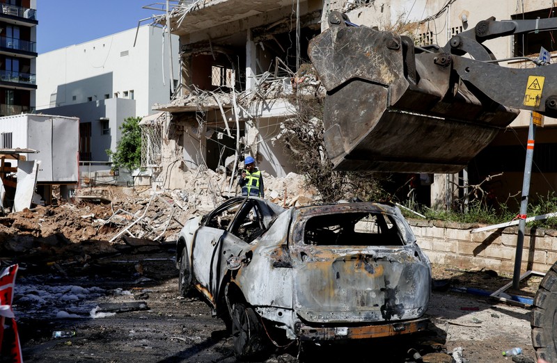 Anggota tim penyelamat bekerja di samping bangunan yang hancur di lokasi kejadian setelah serangan rudal Iran di Israel tengah, di tengah konflik AS-Israel dengan Iran, di Tel Aviv, Israel, Selasa (24/3/2026). (REUTERS/Tomer Appelbaum)