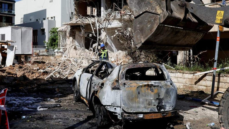 Anggota tim penyelamat bekerja di samping bangunan yang hancur di lokasi kejadian setelah serangan rudal Iran di Israel tengah, di tengah konflik AS-Israel dengan Iran, di Tel Aviv, Israel, Selasa (24/3/2026). (REUTERS/Tomer Appelbaum)
