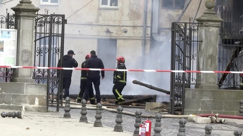 Warga melihat petugas pemadam kebakaran yang bekerja di lokasi bangunan yang terkena serangan pesawat tak berawak Rusia, di tengah serangan Rusia terhadap Ukraina, di pusat kota Lviv, Ukraina, 24 Maret 2026. (REUTERS/Stringer)