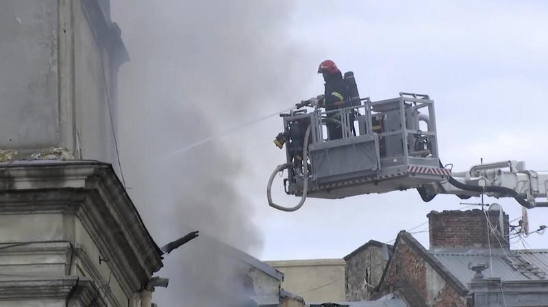 Warga melihat petugas pemadam kebakaran yang bekerja di lokasi bangunan yang terkena serangan pesawat tak berawak Rusia, di tengah serangan Rusia terhadap Ukraina, di pusat kota Lviv, Ukraina, 24 Maret 2026. (REUTERS/Stringer)