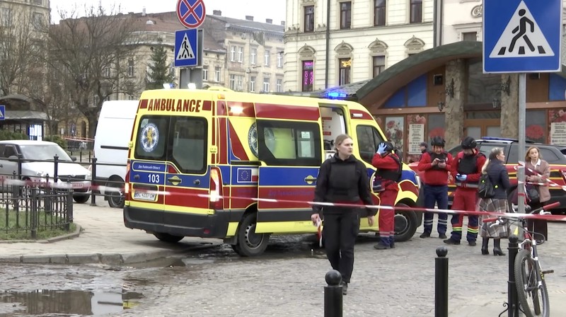 Warga melihat petugas pemadam kebakaran yang bekerja di lokasi bangunan yang terkena serangan pesawat tak berawak Rusia, di tengah serangan Rusia terhadap Ukraina, di pusat kota Lviv, Ukraina, 24 Maret 2026. (REUTERS/Stringer)