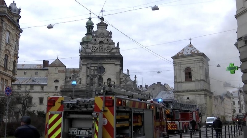 Warga melihat petugas pemadam kebakaran yang bekerja di lokasi bangunan yang terkena serangan pesawat tak berawak Rusia, di tengah serangan Rusia terhadap Ukraina, di pusat kota Lviv, Ukraina, 24 Maret 2026. (REUTERS/Stringer)