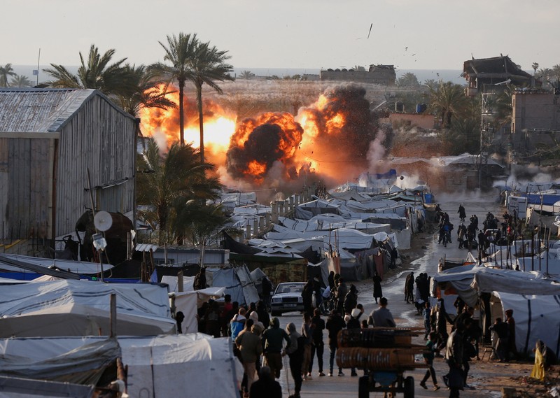 Smoke and flames rise following an Israeli strike near a tent camp sheltering displaced Palestinians in Deir al-Balah, central Gaza Strip, March 25, 2026. The Israeli military ordered camp to evacuate before the strike, according to residents. REUTERS/Stringer