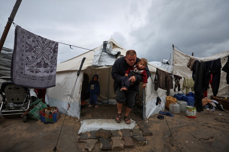 Para pengungsi Palestina berlindung di sebuah kamp tenda pada hari hujan di Kota Gaza, 26 Maret 2026. (REUTERS/Dawoud Abu Alkas)