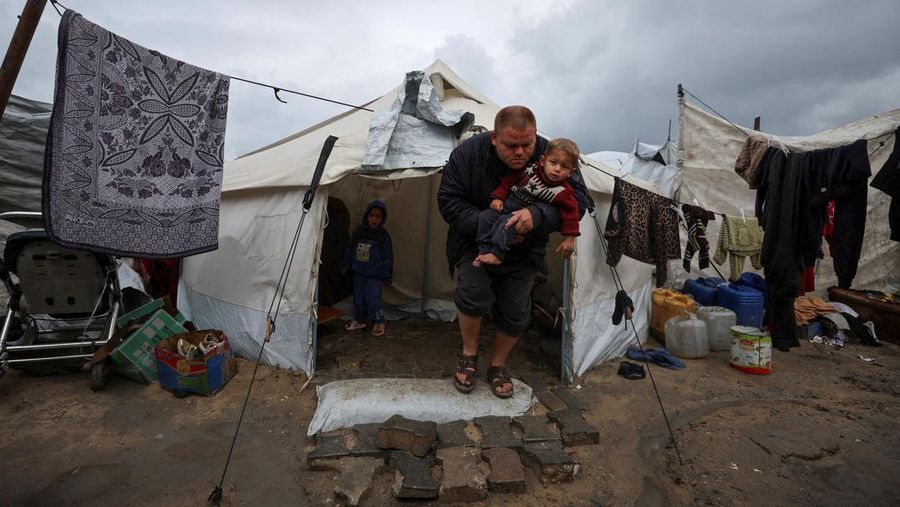 Para pengungsi Palestina berlindung di sebuah kamp tenda pada hari hujan di Kota Gaza, 26 Maret 2026. (REUTERS/Dawoud Abu Alkas)
