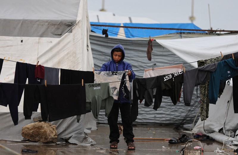 Para pengungsi Palestina berlindung di sebuah kamp tenda pada hari hujan di Kota Gaza, 26 Maret 2026. (REUTERS/Dawoud Abu Alkas)