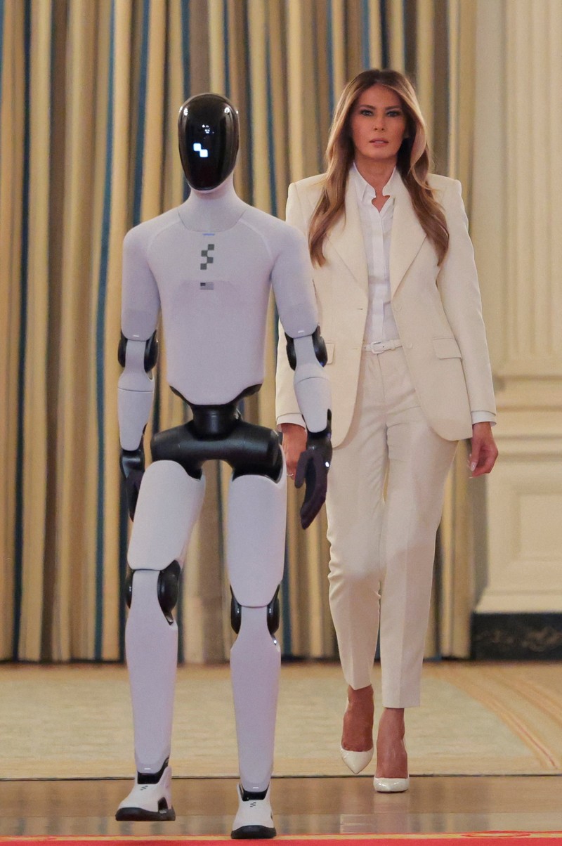 U.S. first lady Melania Trump walks next to a humanoid robot as she hosts a roundtable event on the second day of the inaugural Fostering the Future Together Global Coalition Summit, at the White House in Washington, D.C., U.S., March 25, 2026. REUTERS/Kylie Cooper      TPX IMAGES OF THE DAY