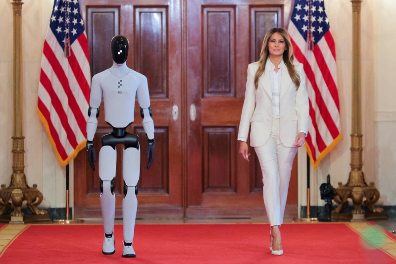 U.S. first lady Melania Trump walks next to a humanoid robot as she hosts a roundtable event on the second day of the inaugural Fostering the Future Together Global Coalition Summit, at the White House in Washington, D.C., U.S., March 25, 2026. REUTERS/Kylie Cooper      TPX IMAGES OF THE DAY