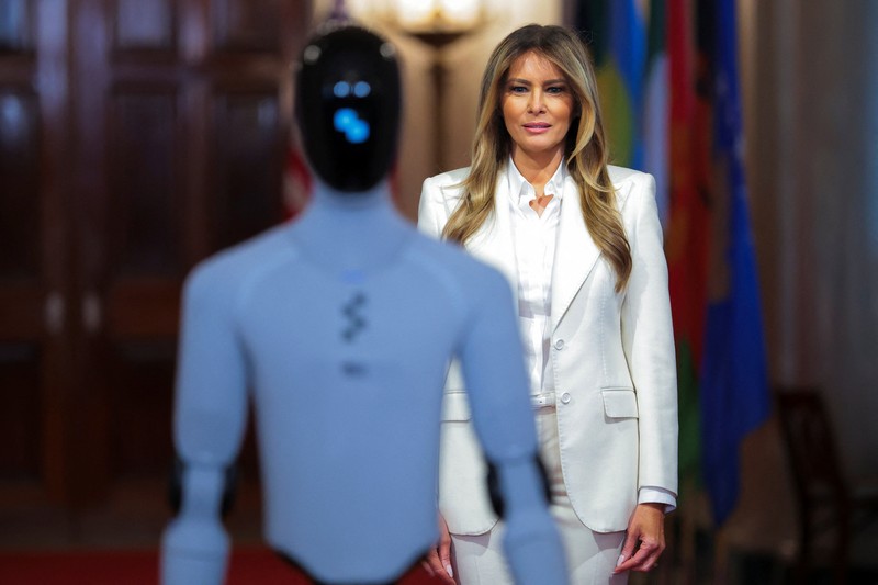 U.S. first lady Melania Trump walks next to a humanoid robot as she hosts a roundtable event on the second day of the inaugural Fostering the Future Together Global Coalition Summit, at the White House in Washington, D.C., U.S., March 25, 2026. REUTERS/Kylie Cooper      TPX IMAGES OF THE DAY