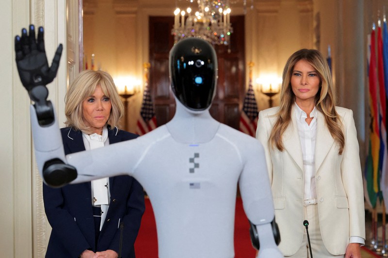U.S. first lady Melania Trump walks next to a humanoid robot as she hosts a roundtable event on the second day of the inaugural Fostering the Future Together Global Coalition Summit, at the White House in Washington, D.C., U.S., March 25, 2026. REUTERS/Kylie Cooper      TPX IMAGES OF THE DAY
