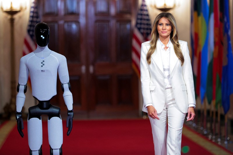 U.S. first lady Melania Trump walks next to a humanoid robot as she hosts a roundtable event on the second day of the inaugural Fostering the Future Together Global Coalition Summit, at the White House in Washington, D.C., U.S., March 25, 2026. REUTERS/Kylie Cooper      TPX IMAGES OF THE DAY