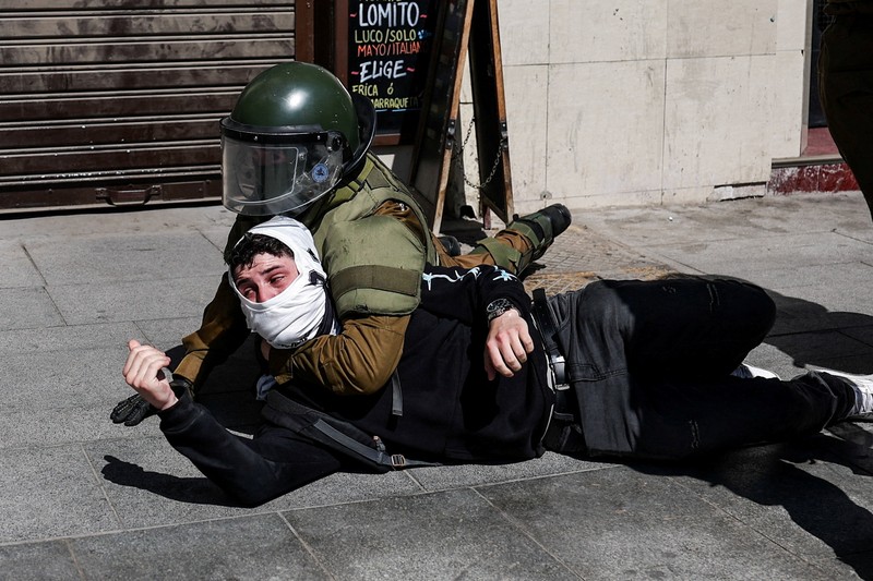 A demonstrator throws an object as a water cannon is used during a protest against the Chilean government's budget cuts to education, in Santiago, Chile, March 26, 2026. REUTERS/Pablo Sanhueza