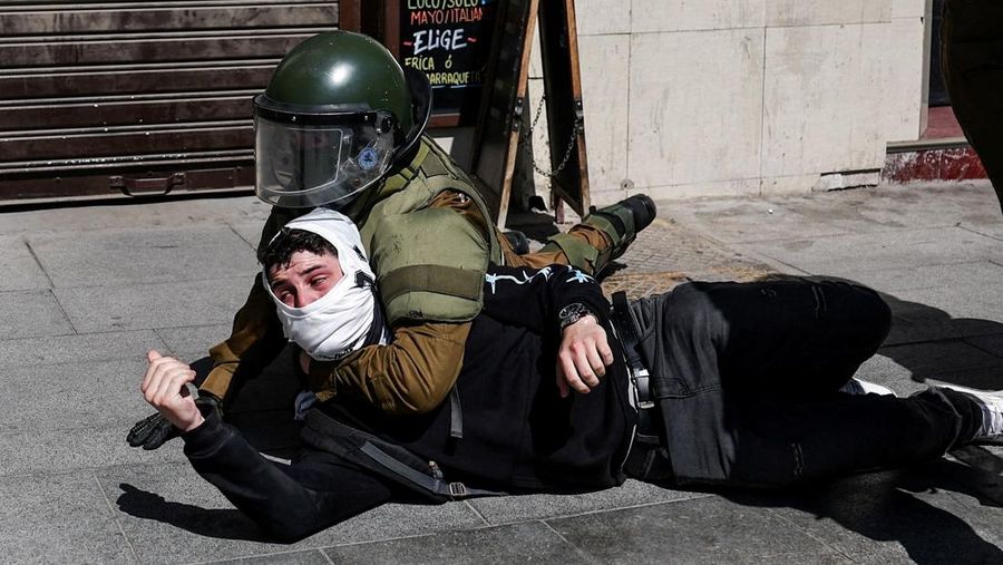 A demonstrator throws an object as a water cannon is used during a protest against the Chilean government's budget cuts to education, in Santiago, Chile, March 26, 2026. REUTERS/Pablo Sanhueza
