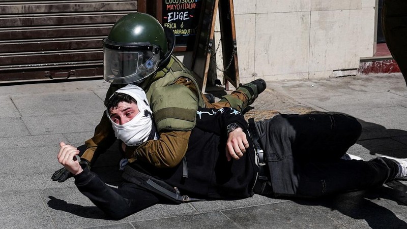 A demonstrator throws an object as a water cannon is used during a protest against the Chilean government's budget cuts to education, in Santiago, Chile, March 26, 2026. REUTERS/Pablo Sanhueza