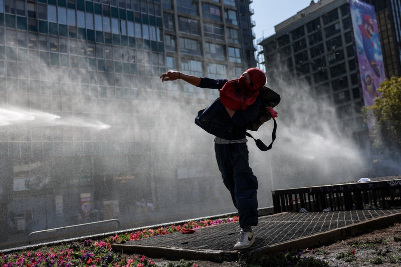 A demonstrator throws an object as a water cannon is used during a protest against the Chilean government's budget cuts to education, in Santiago, Chile, March 26, 2026. REUTERS/Pablo Sanhueza