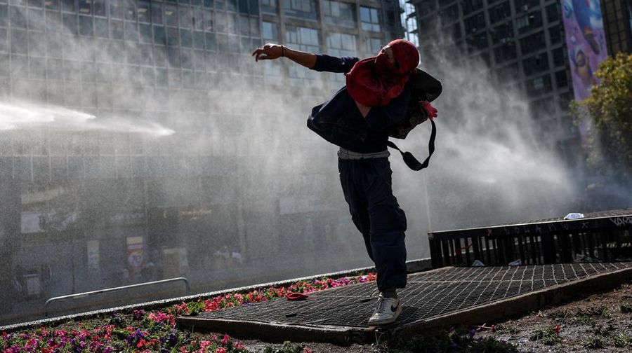 A demonstrator throws an object as a water cannon is used during a protest against the Chilean government's budget cuts to education, in Santiago, Chile, March 26, 2026. REUTERS/Pablo Sanhueza