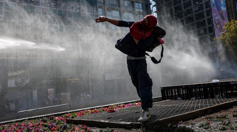 A demonstrator throws an object as a water cannon is used during a protest against the Chilean government's budget cuts to education, in Santiago, Chile, March 26, 2026. REUTERS/Pablo Sanhueza