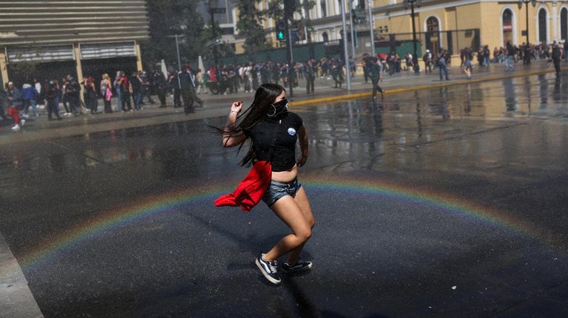 A demonstrator throws an object as a water cannon is used during a protest against the Chilean government's budget cuts to education, in Santiago, Chile, March 26, 2026. REUTERS/Pablo Sanhueza